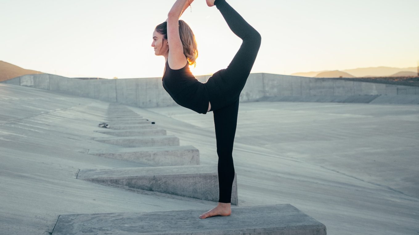 shallow focus photo of woman in black sleeveless shirt doing yoga